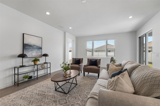 living room with visible vents, baseboards, wood finished floors, and recessed lighting