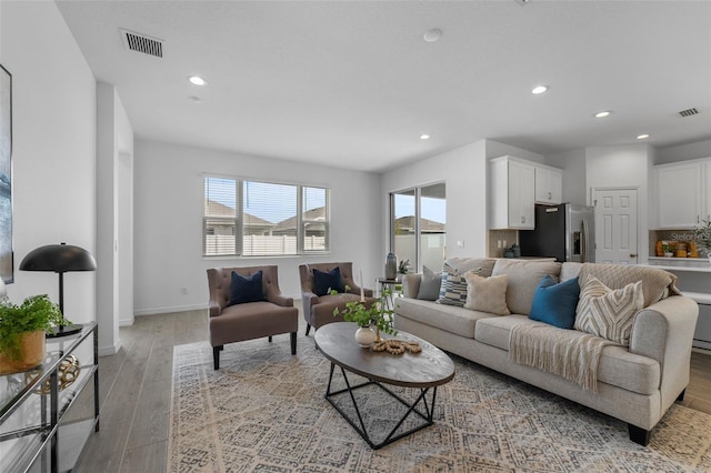 living area with light wood-style floors, a wealth of natural light, visible vents, and baseboards