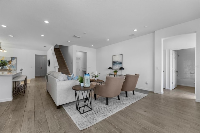 living area with recessed lighting, visible vents, stairway, and light wood finished floors