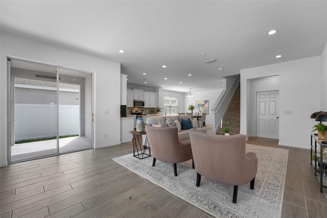 living room with recessed lighting, wood finished floors, baseboards, and stairs