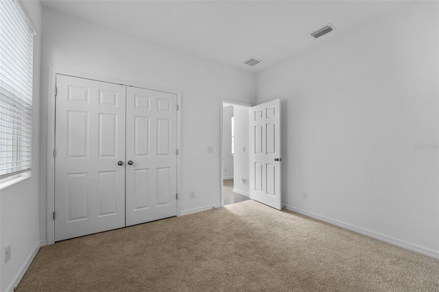 unfurnished bedroom with a closet, carpet flooring, visible vents, and baseboards