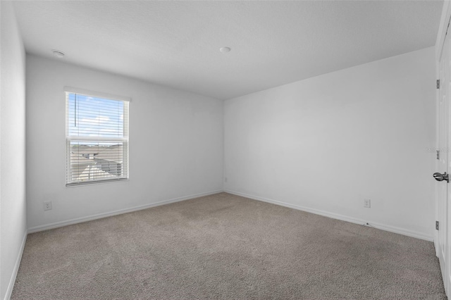 carpeted spare room featuring baseboards