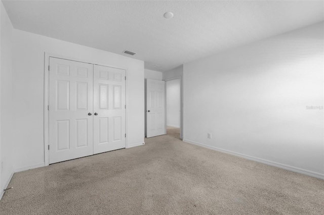 unfurnished bedroom featuring baseboards, carpet, visible vents, and a closet