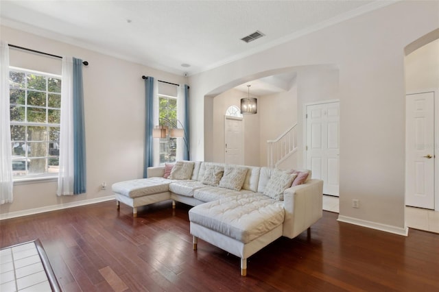 living room with arched walkways, visible vents, baseboards, and wood finished floors