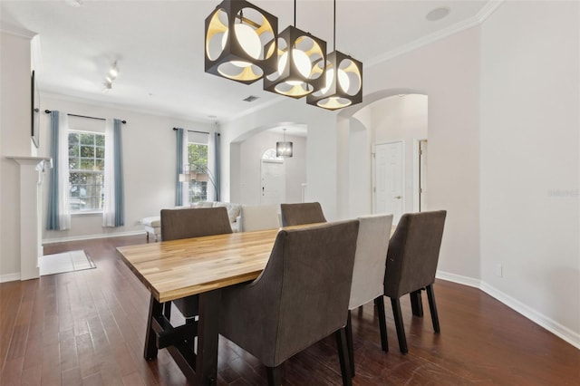 dining room with dark wood-style floors, baseboards, arched walkways, and crown molding