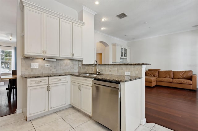 kitchen with stainless steel dishwasher, a sink, visible vents, and tasteful backsplash