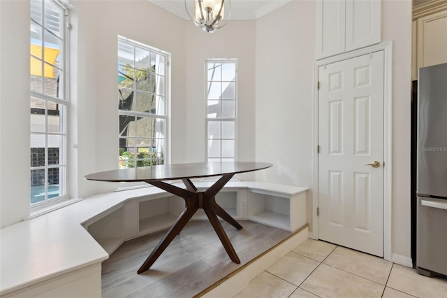 dining area featuring breakfast area, a notable chandelier, ornamental molding, and light tile patterned floors