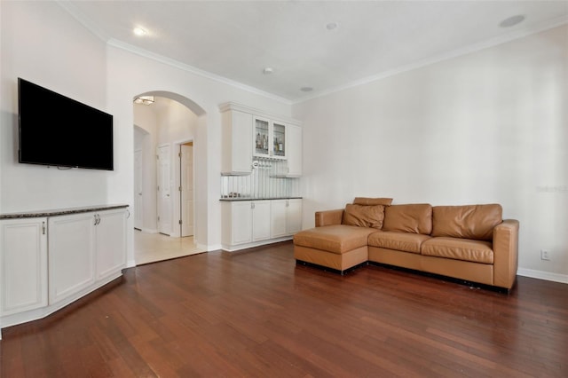 living area featuring baseboards, crown molding, arched walkways, and dark wood-type flooring