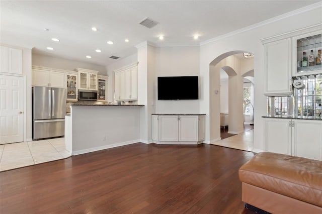 living area featuring arched walkways, recessed lighting, visible vents, ornamental molding, and wood finished floors