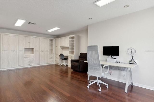 home office featuring baseboards, visible vents, dark wood finished floors, and built in desk