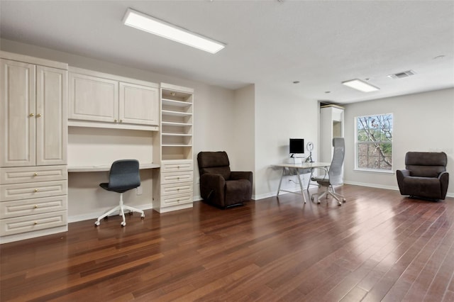 office area with baseboards, visible vents, dark wood-type flooring, and built in desk