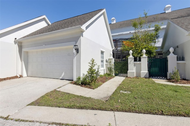 view of side of property with an attached garage, fence, driveway, a gate, and stucco siding