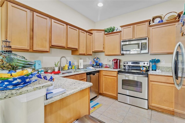 kitchen featuring appliances with stainless steel finishes, a peninsula, light stone countertops, a sink, and light tile patterned flooring