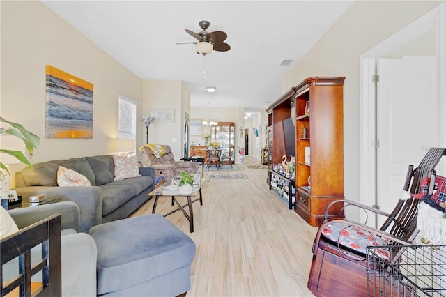 living room with visible vents, light wood finished floors, and ceiling fan with notable chandelier