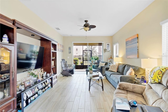 living room with light wood-style flooring, visible vents, and a ceiling fan