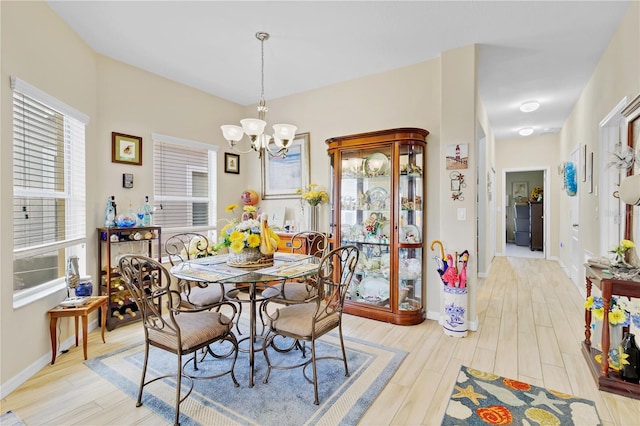 dining space featuring light wood-type flooring, baseboards, and an inviting chandelier