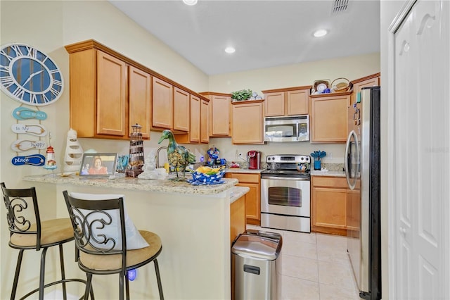 kitchen featuring light stone counters, light tile patterned flooring, stainless steel appliances, a peninsula, and visible vents