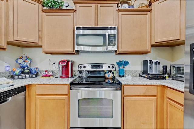 kitchen featuring a toaster, appliances with stainless steel finishes, and light brown cabinetry