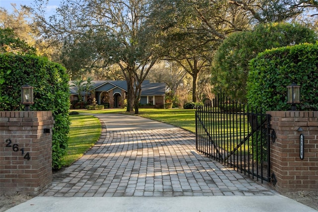 view of gate with fence and a lawn