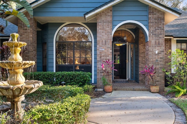 property entrance with a shingled roof and brick siding