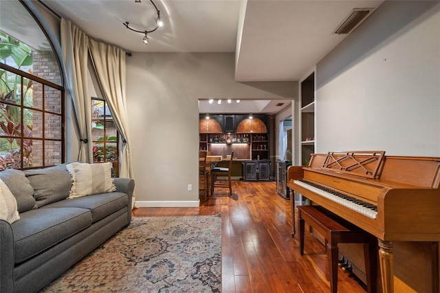 living room featuring track lighting, wood-type flooring, visible vents, and baseboards