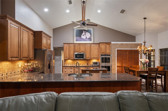 kitchen featuring stainless steel appliances, a peninsula, a sink, visible vents, and dark stone countertops