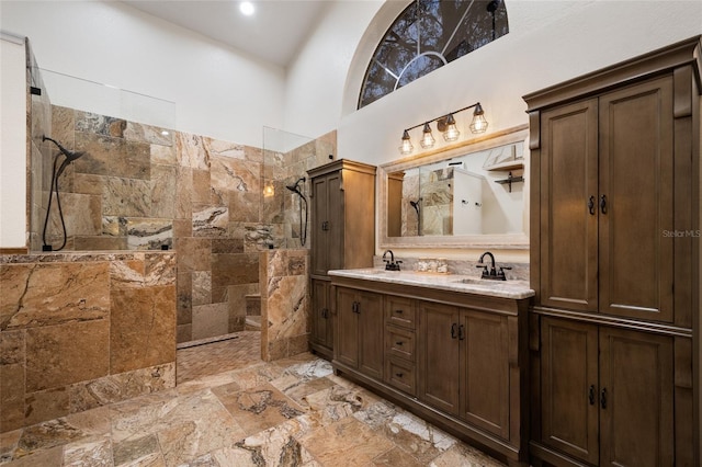 bathroom featuring a walk in shower, double vanity, a high ceiling, and a sink