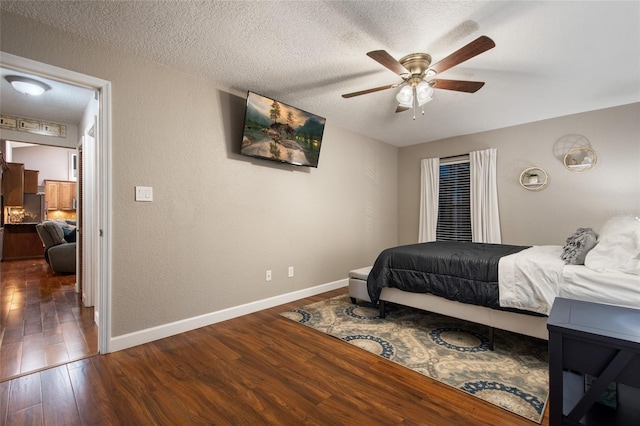 bedroom featuring a textured wall, ceiling fan, a textured ceiling, wood finished floors, and baseboards