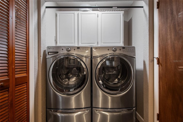 washroom with a textured wall, cabinet space, and independent washer and dryer