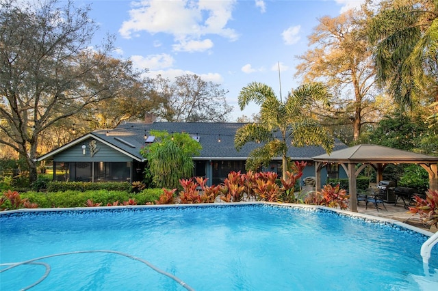 outdoor pool featuring a gazebo, a patio, a grill, and a sunroom