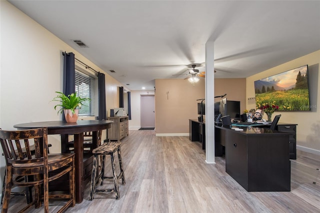 dining room featuring light wood-style flooring, a ceiling fan, visible vents, and baseboards