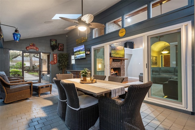 interior space featuring an outdoor brick fireplace, outdoor dining area, and a ceiling fan