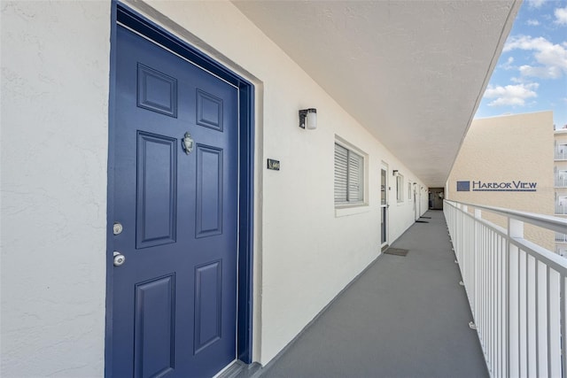 property entrance with a balcony and stucco siding