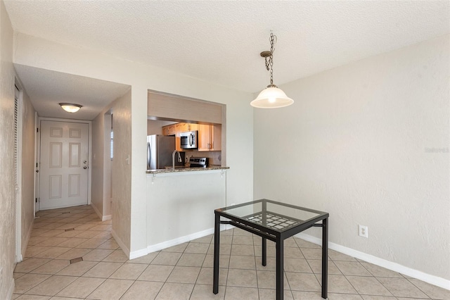 unfurnished dining area featuring a textured ceiling, baseboards, and light tile patterned floors