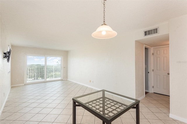 spare room with baseboards, visible vents, a textured ceiling, and light tile patterned flooring