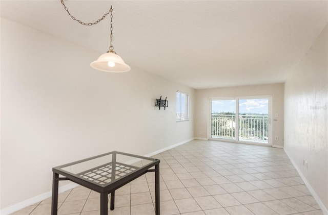 spare room featuring light tile patterned flooring and baseboards