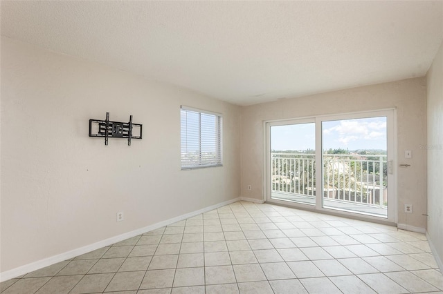 unfurnished room featuring light tile patterned flooring, plenty of natural light, and baseboards