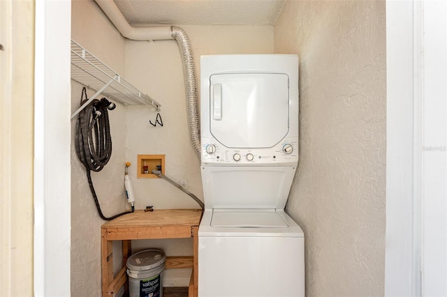 laundry area with laundry area, stacked washer / dryer, and a textured wall