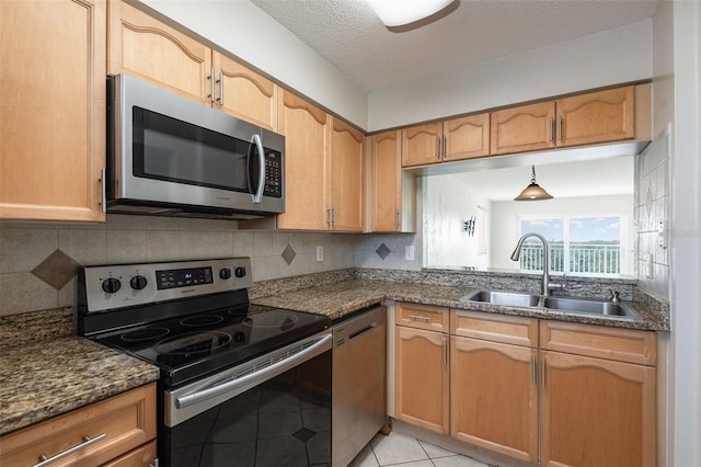 kitchen featuring light tile patterned floors, tasteful backsplash, appliances with stainless steel finishes, a sink, and a textured ceiling