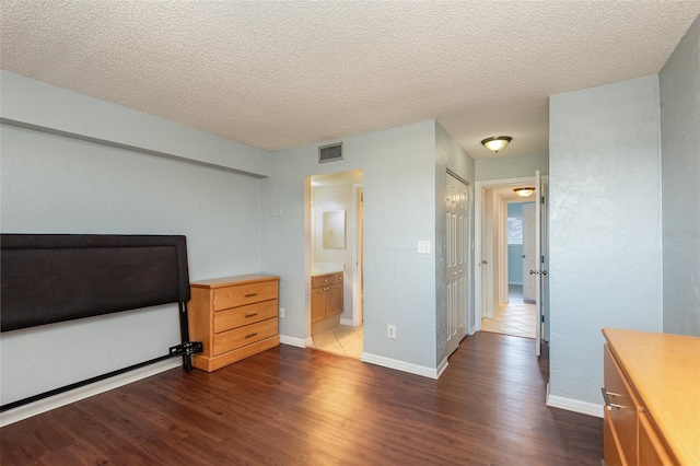 bedroom featuring visible vents, dark wood finished floors, and a textured ceiling