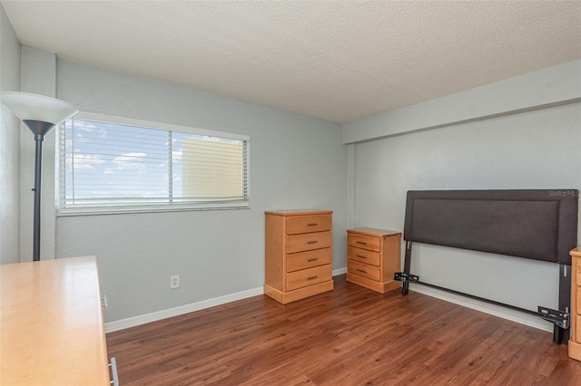 unfurnished bedroom with a textured ceiling, baseboards, and wood finished floors