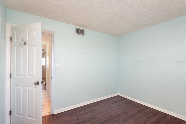 spare room with visible vents, dark wood finished floors, and baseboards