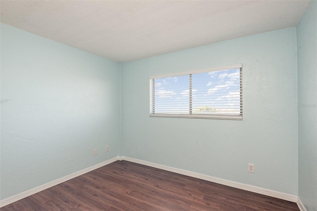 unfurnished room with baseboards, dark wood finished floors, and a textured ceiling