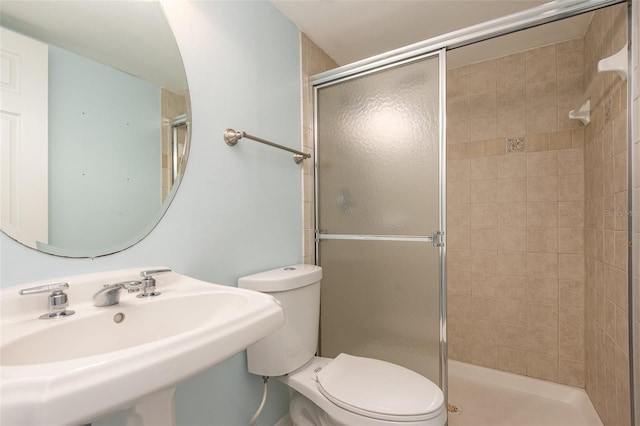 bathroom with a sink, a shower stall, and toilet