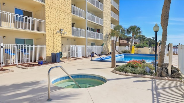 pool with a community hot tub, a patio area, and fence