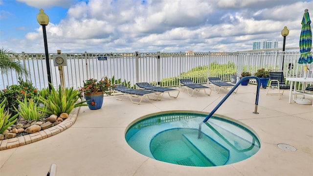 view of pool with a patio area, fence, and a hot tub