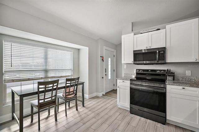 kitchen with stainless steel appliances, wood finish floors, white cabinetry, and plenty of natural light