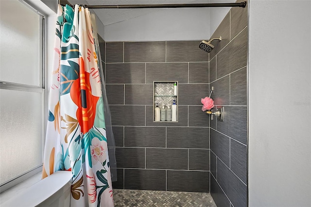 full bathroom featuring a tile shower and toilet