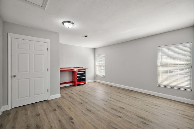 empty room with baseboards, visible vents, and wood finished floors