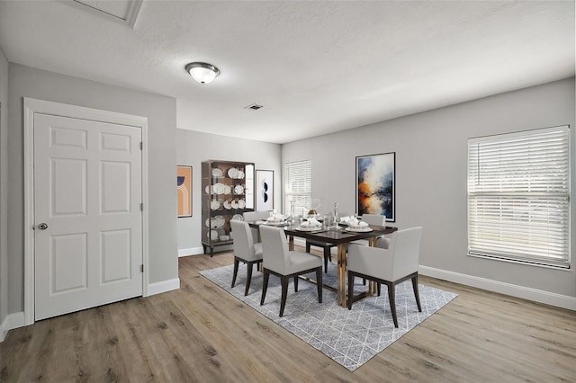 dining room with visible vents, baseboards, and wood finished floors